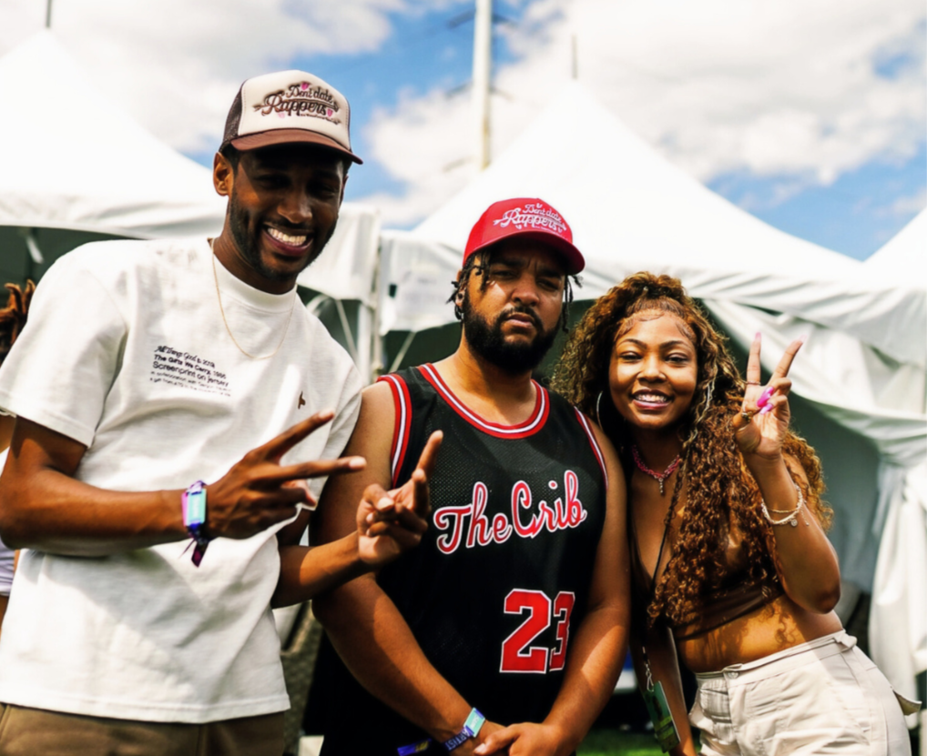 Three people posing together with The Crib Jersey at an outdoor event.