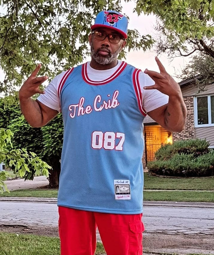 Person wearing a blue and red sports jersey with 'The Crib' and '087' text, standing on a sidewalk.